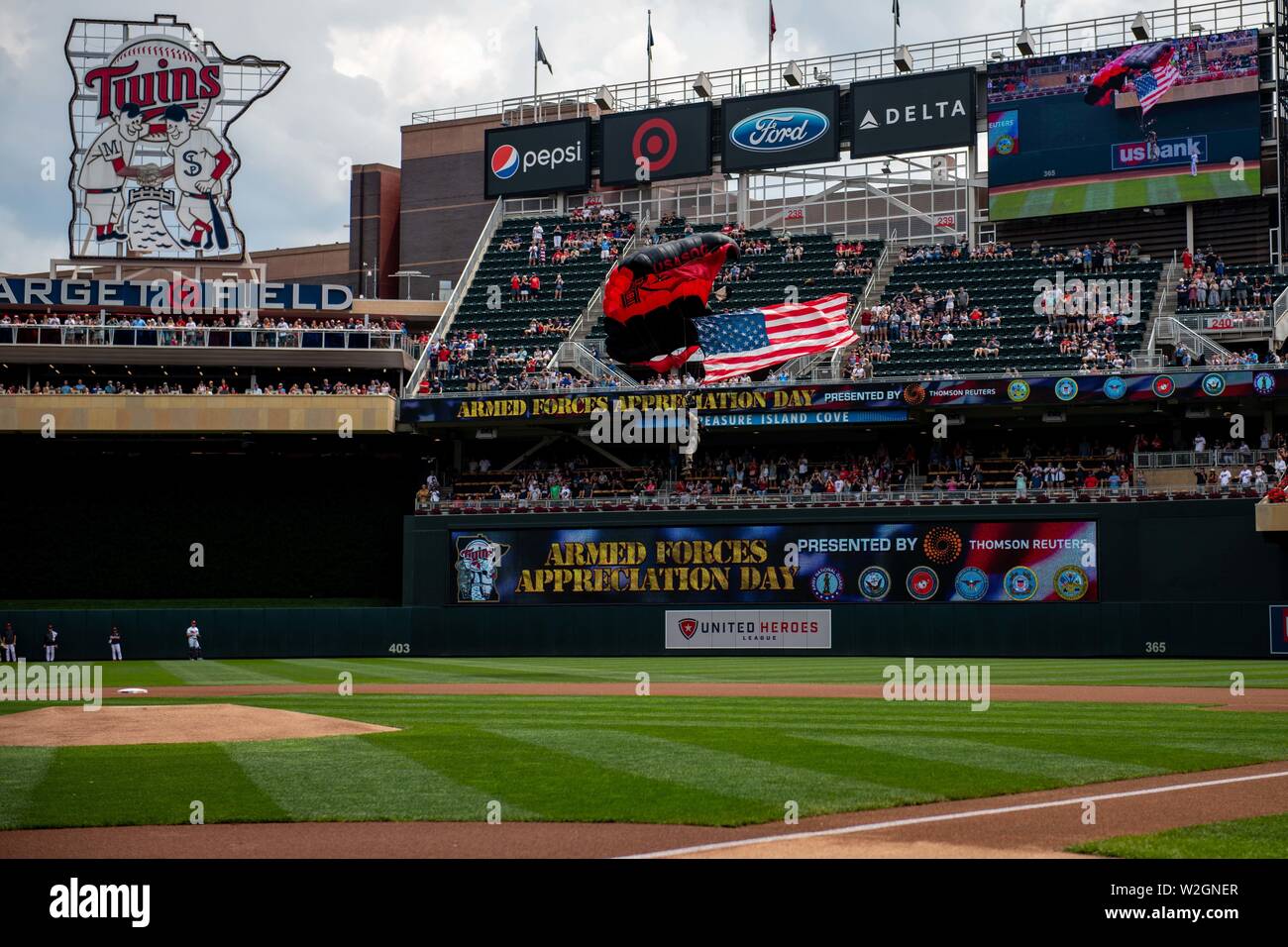 Sgt. Erste Klasse Sean O'Toole der U.S. Army Special Operations Command's Black Daggers Fallschirm demonstration Team gleitet in Feld Ziel während der 16. jährlichen Minnesota Twins Streitkräfte Anerkennung Tag am 7. Juli 2019, in Minneapolis, während fliegen die amerikanische Flagge und die Durchführung des Spiels Ball. Jeder der Soldaten Gleiten bei zwischen 600 und 4.000 Sprünge gemacht hat. (Minnesota National Guard Foto von Sgt. Sebastian Nemec) Stockfoto