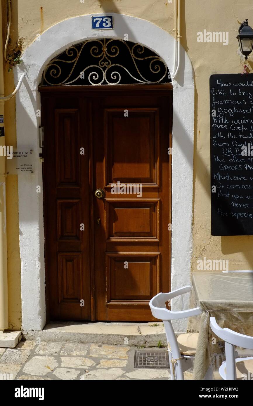 Braun getäfelten Tür im Torbogen im Schatten in der Stadt Korfu kleine quadratische Paneele und aufwändige Konstruktion über der Tür aus Eiche Stockfoto