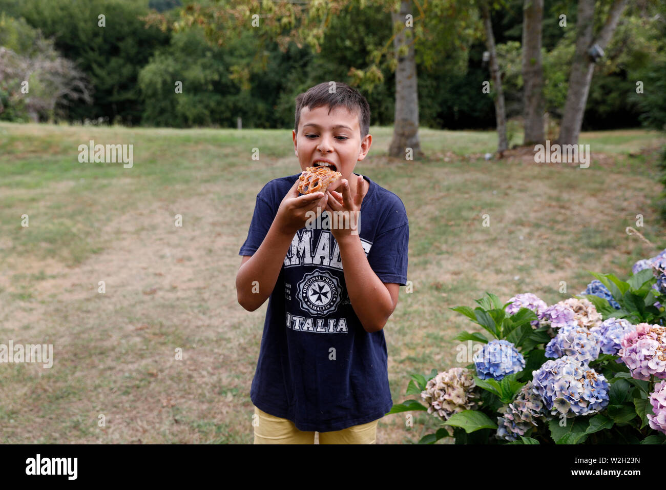 12-jähriger Junge Essen in einem Garten in Bosc-Renoult, Frankreich. Stockfoto 12-jähriger Junge Essen in einem Garten in Bosc-Renoult, Frankreich. Stockfoto