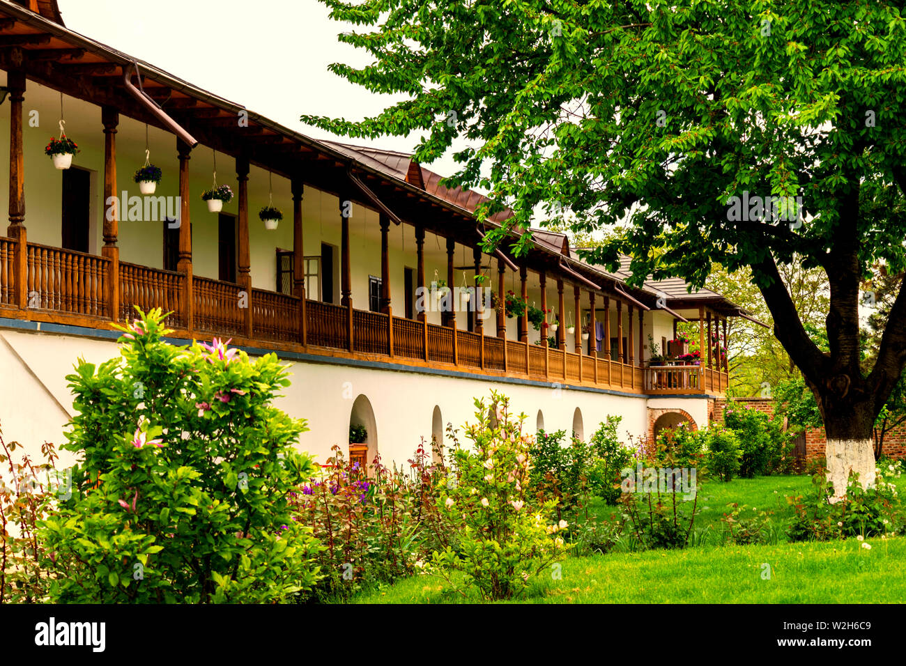 Rustikales Haus im alten Stil mit aufwendigen Holz Veranda und der grünen Garten baum Stockfoto