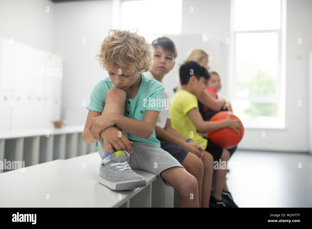 Traurige Schüler sitzen vor seinen Mitschülern. Stockfoto