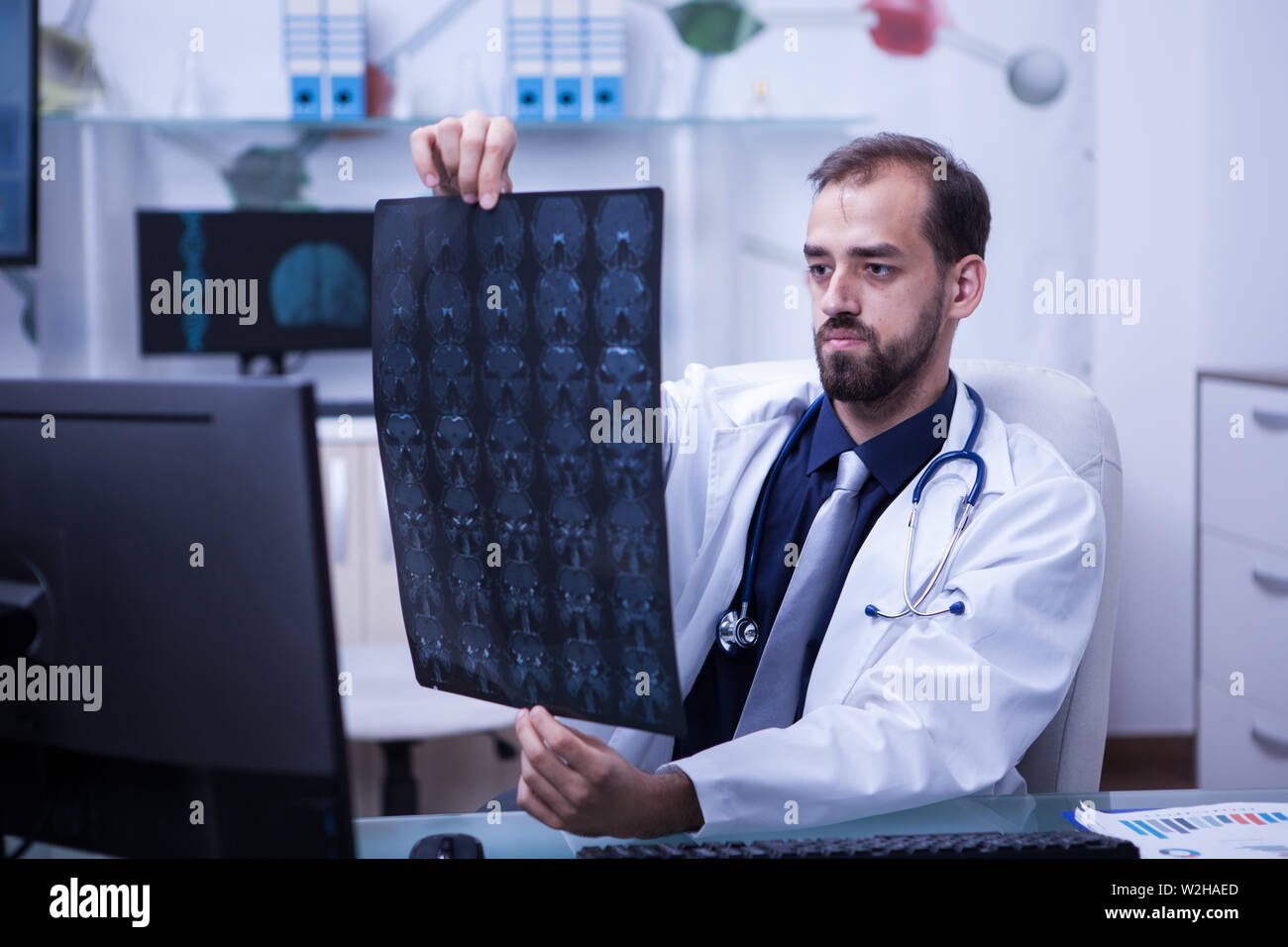 Portrait von hübscher junger Arzt, ein Gehirn, das x-ray suchen. Arzt, eine Diagnose. Gehirn-CT-Scan. Stockfoto