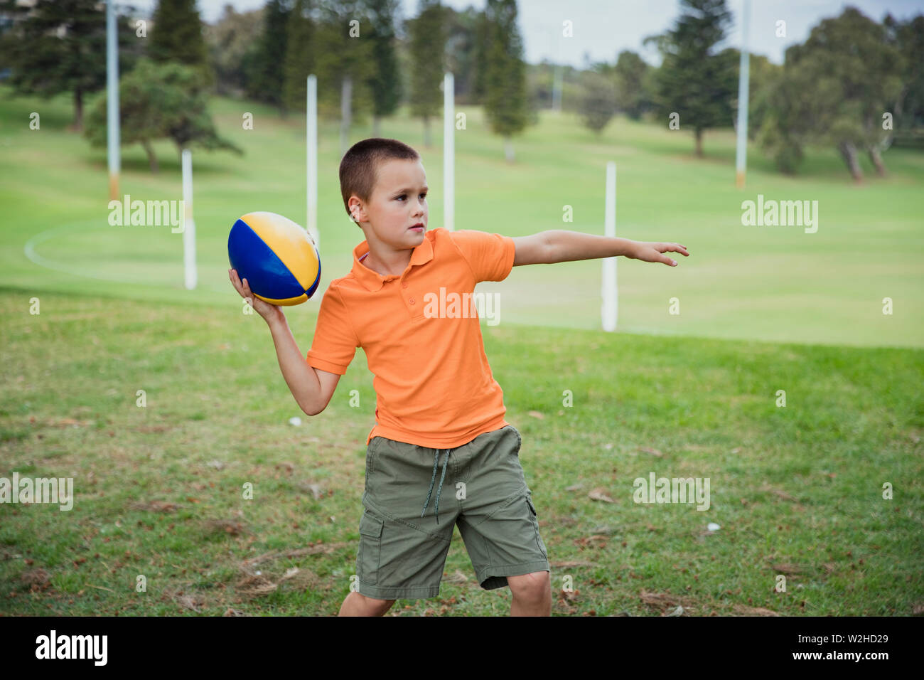 Ein Porträt der jungen kaukasischen Jungen legere Kleidung, hält er einen rugby ball, schaut er in die Kamera. Stockfoto