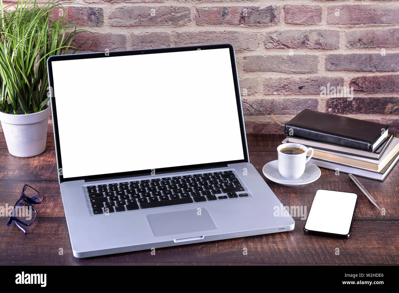 Laptop Notebook mit leerer Bildschirm und Tasse Kaffee und Notizblock Stift und Bücher und Smart-phone auf hölzernen Tisch. Mock up auf Holztisch mit Laptop wi Stockfoto