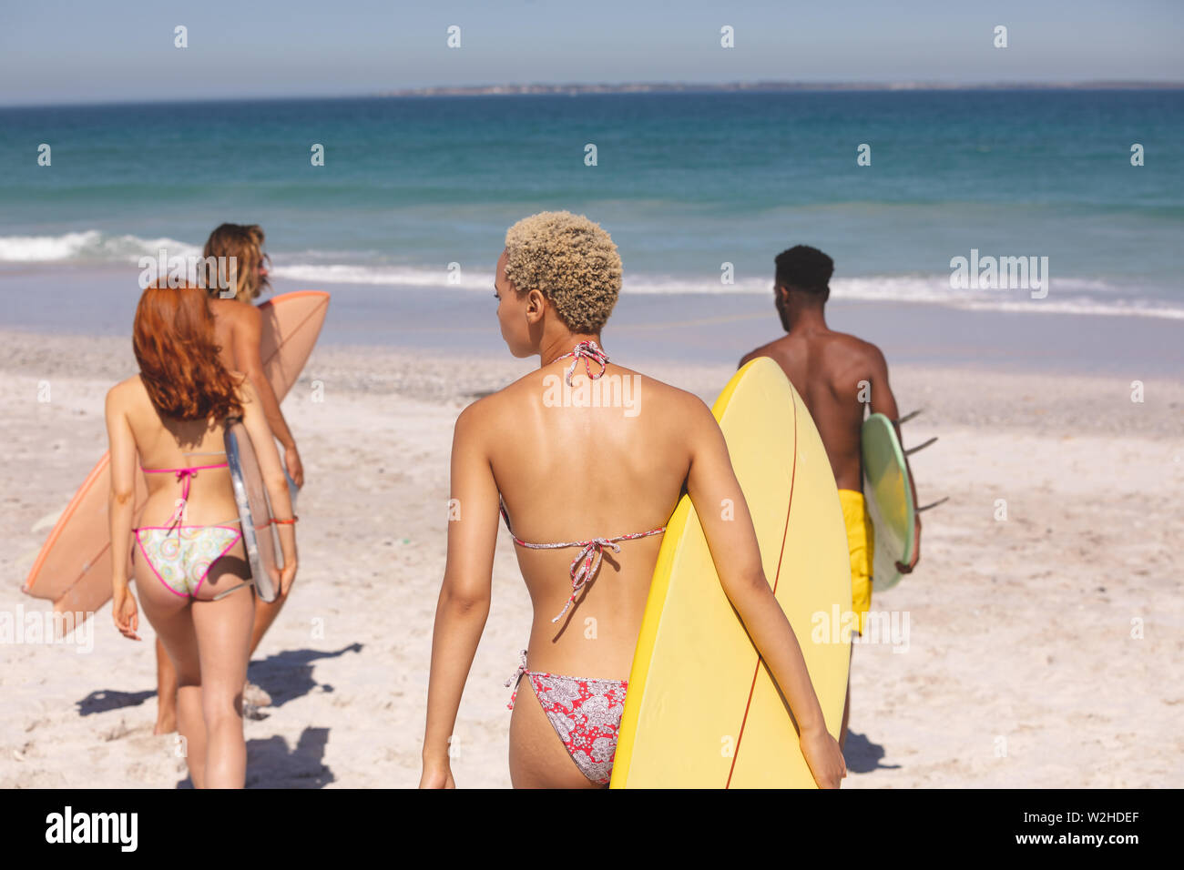 Gruppe von Freunden wandern mit Surfbrett am Strand Stockfoto