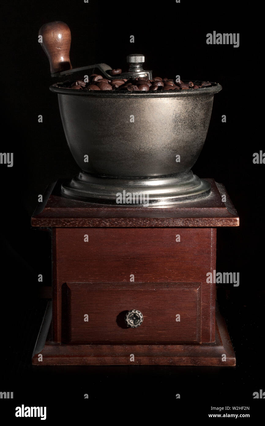 Kaffeemühle voller Kaffeebohnen auf schwarzem Hintergrund Stockfoto