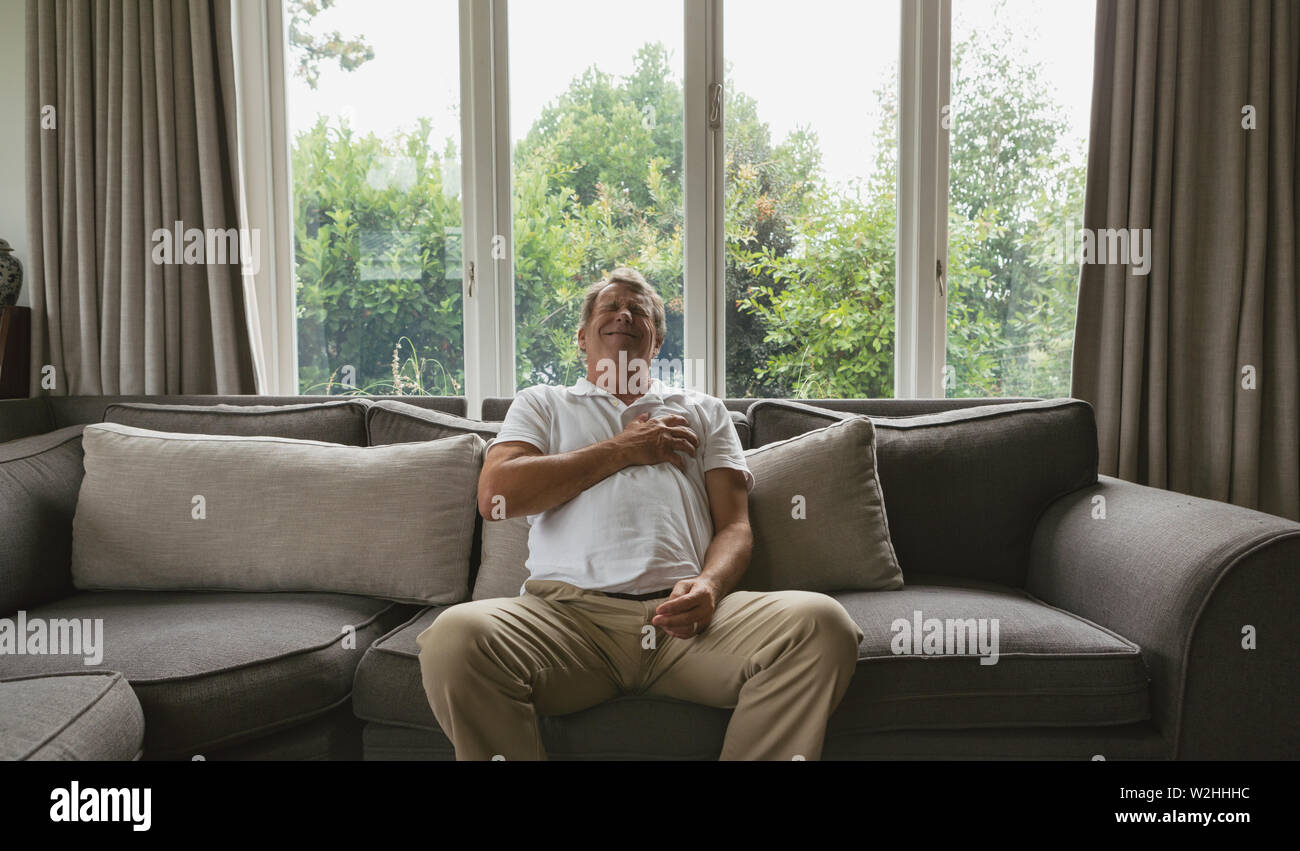 Aktive ältere Menschen leiden unter Schmerzen in der Brust auf dem Sofa in ein gemütliches Heim Stockfoto