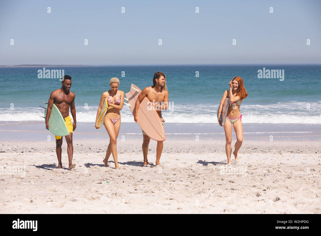 Gruppe von Freunden wandern mit Surfbrett am Strand Stockfoto