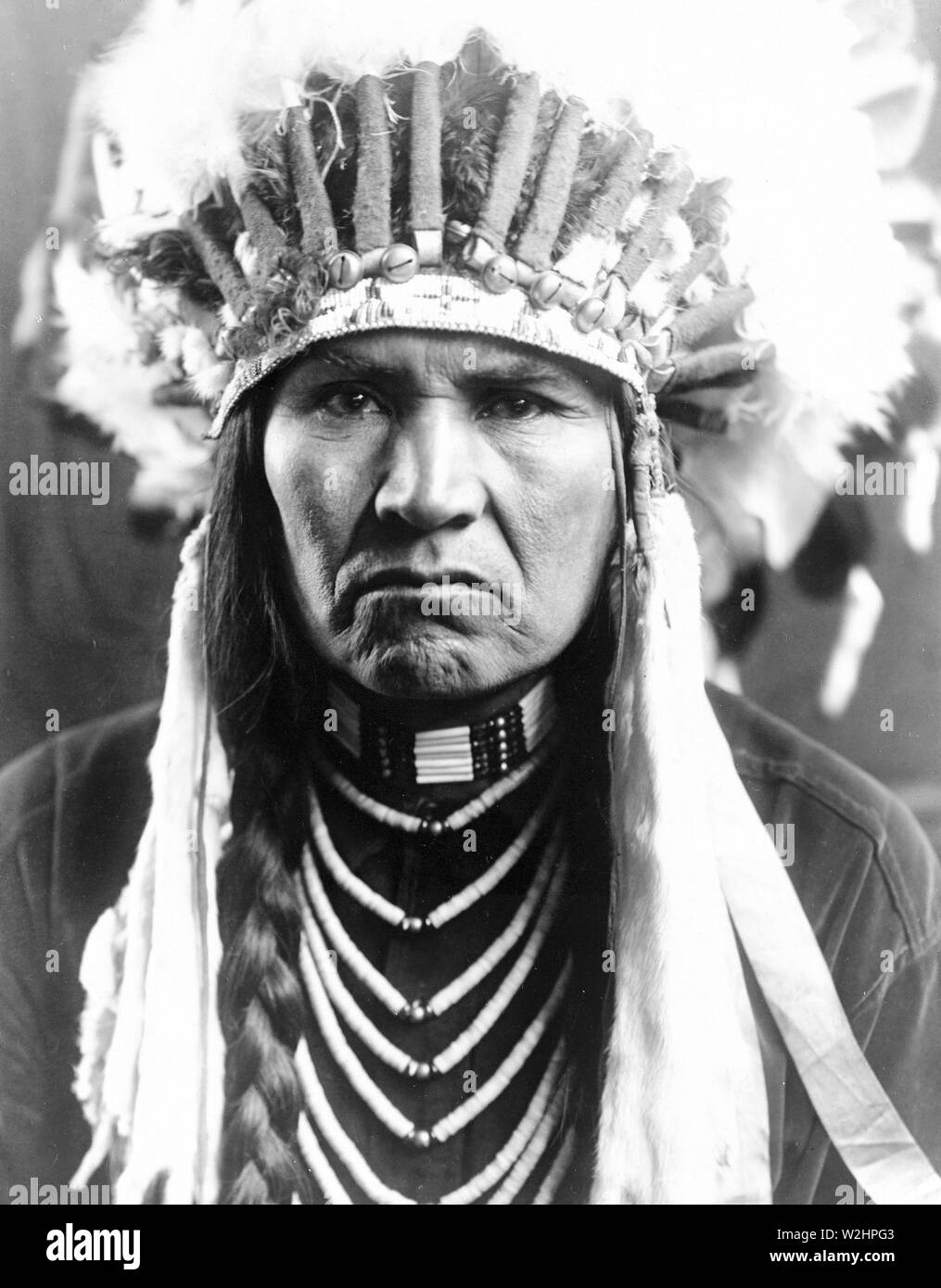 Edward S. Curtis Native American Indians - Nez Percé Mann in voller Federkopfschmuck, geflochtene Haare, und Halsketten Ca. 1910 Stockfoto