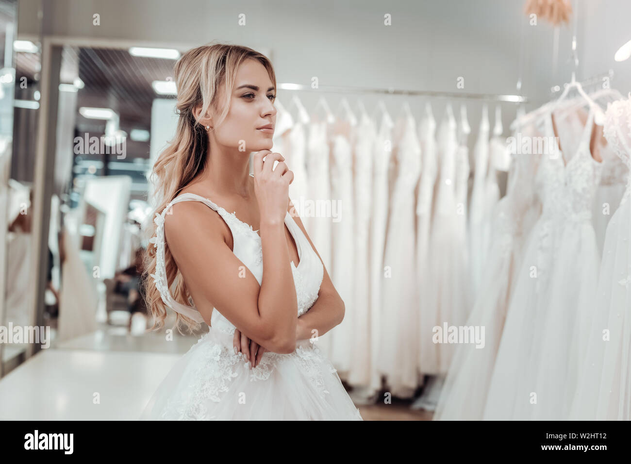 Junge Braut bei der Hochzeit Kleider in einem Geschäft suchen. Stockfoto