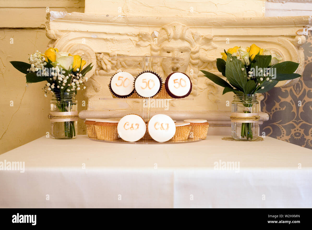 Anzeige der Tabelle mit Gläsern von Blumen und Mini iced Kuchen zum 50. Hochzeitstag feiern ein Paar Stockfoto