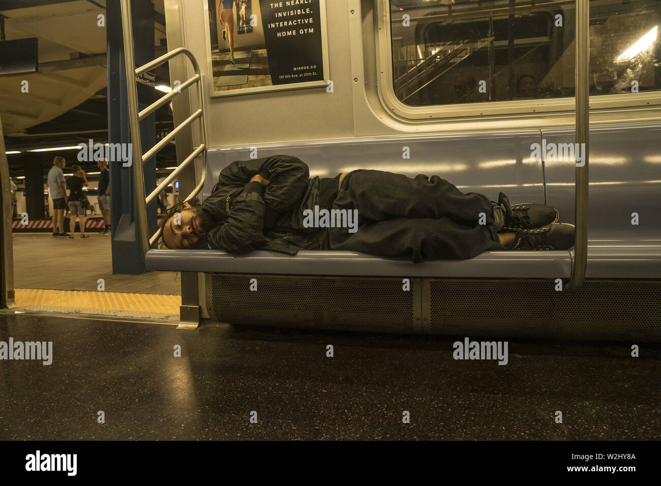 Obdachlosen schläft auf einer U-Bahn in der Jay St-Metrotech station in Brooklyn, New York. Stockfoto
