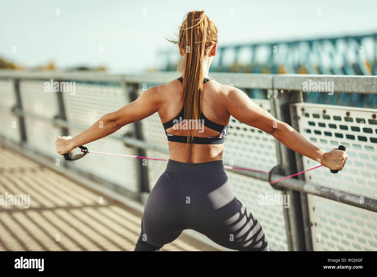 Muskulöse junge Frau tut gut geeignet sind Körper Training mit elastischen Gummiband auf der Brücke. Stockfoto