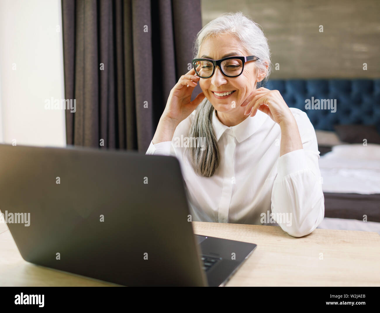 Senior langhaarige Frau mit Brille mit Videochat und hat nettes Gespräch Stockfoto
