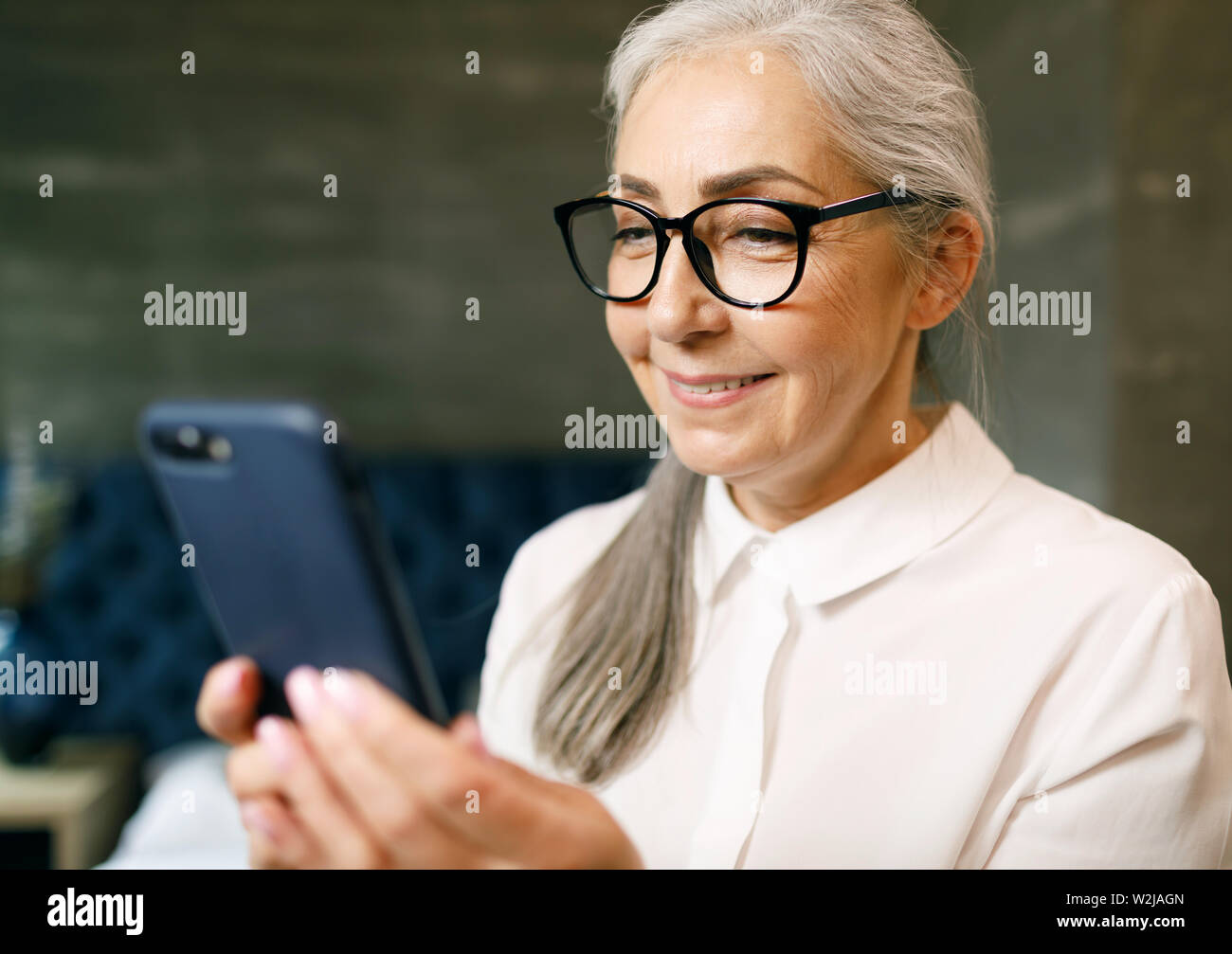 Ältere Frau mit grauen Haaren in Brillen mit Smartphone Stockfoto