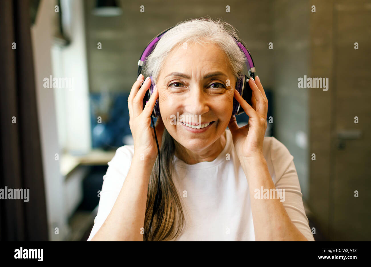 Ältere Frau mit weißen Haaren in Kopfhörer Ihre Lieblingsmusik hören Stockfoto