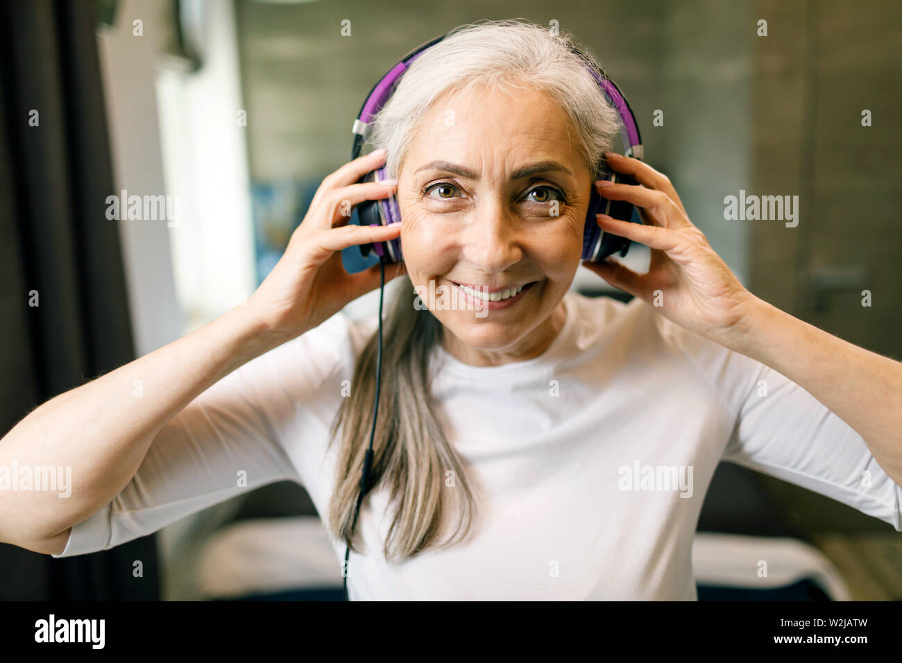 Grauen Haaren ältere Frau trägt Kopfhörer Anhören der Musik Stockfoto
