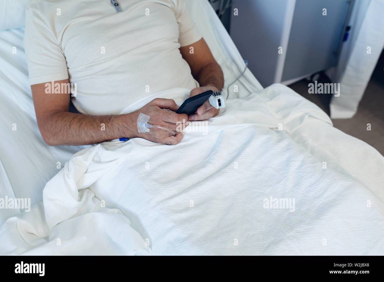 Männliche Patienten mit Handy in der Gemeinde, im Krankenhaus Stockfoto