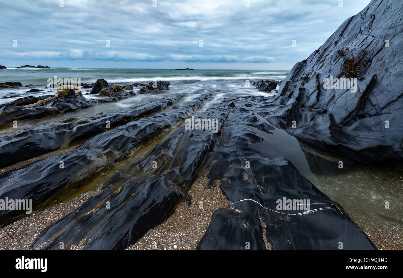 Wellen um die Felsen am Ayrmer Cove in Devon Stockfoto
