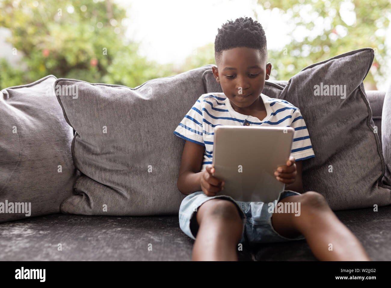 Junge mit digitalen Tablet auf einem Sofa im Wohnzimmer. Stockfoto