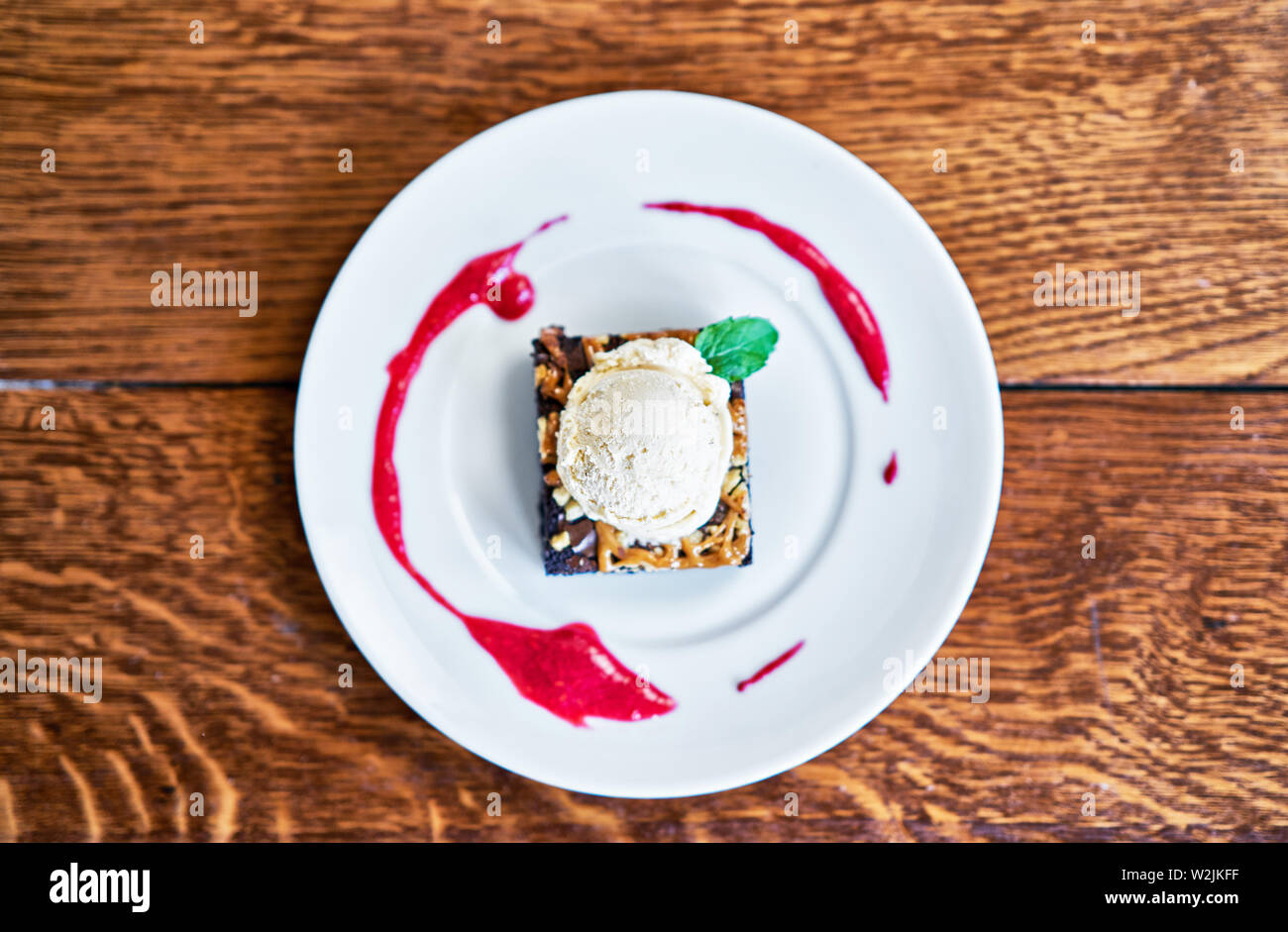 Brownie Sundae mit einer Kugel Vanilleeis und Berry Sauce Stockfoto