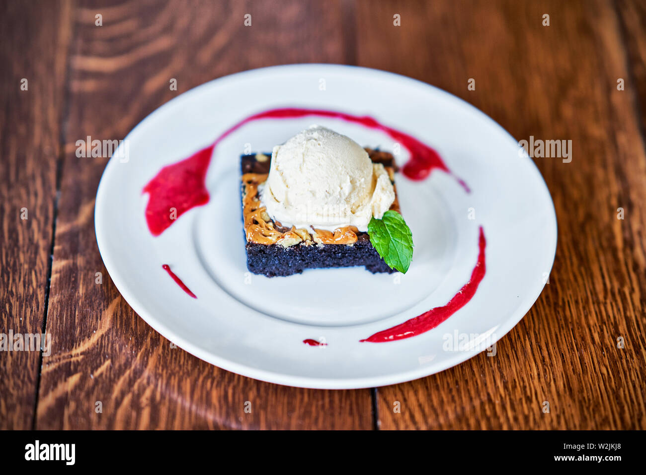 Brownie Sundae mit einer Kugel Vanilleeis und Berry Sauce Stockfoto