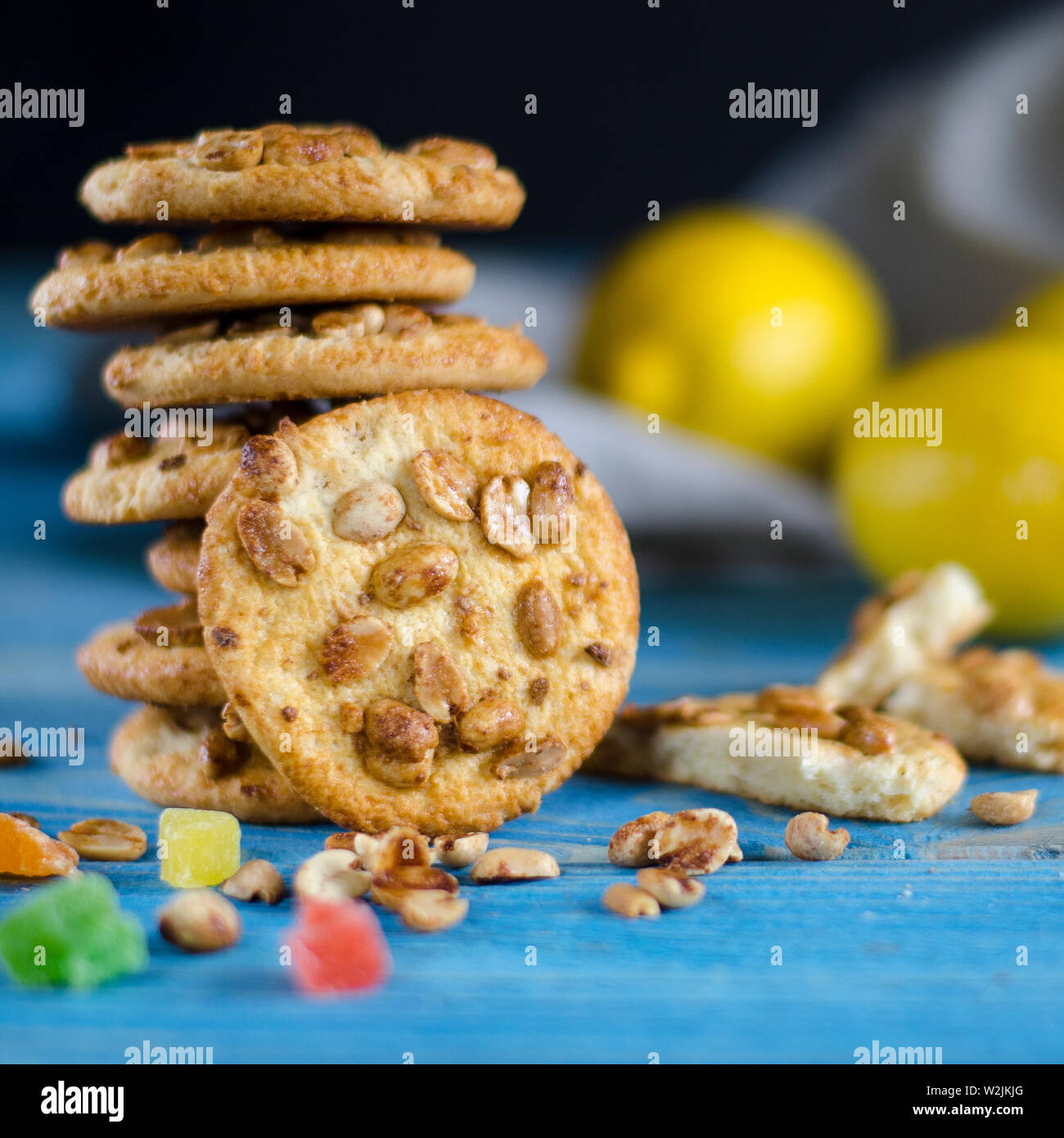 Runde orange Biscuits mit bunten kandierte Früchte und ein Stück saftige Orange liegen auf einem Holztisch Stockfoto