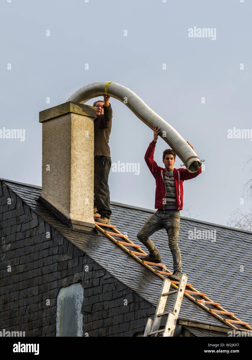 Zwei Männer ohne Sicherheitsausrüstung auf haus dach Einbau Schächte in die inländische Schornstein - Frankreich. Stockfoto