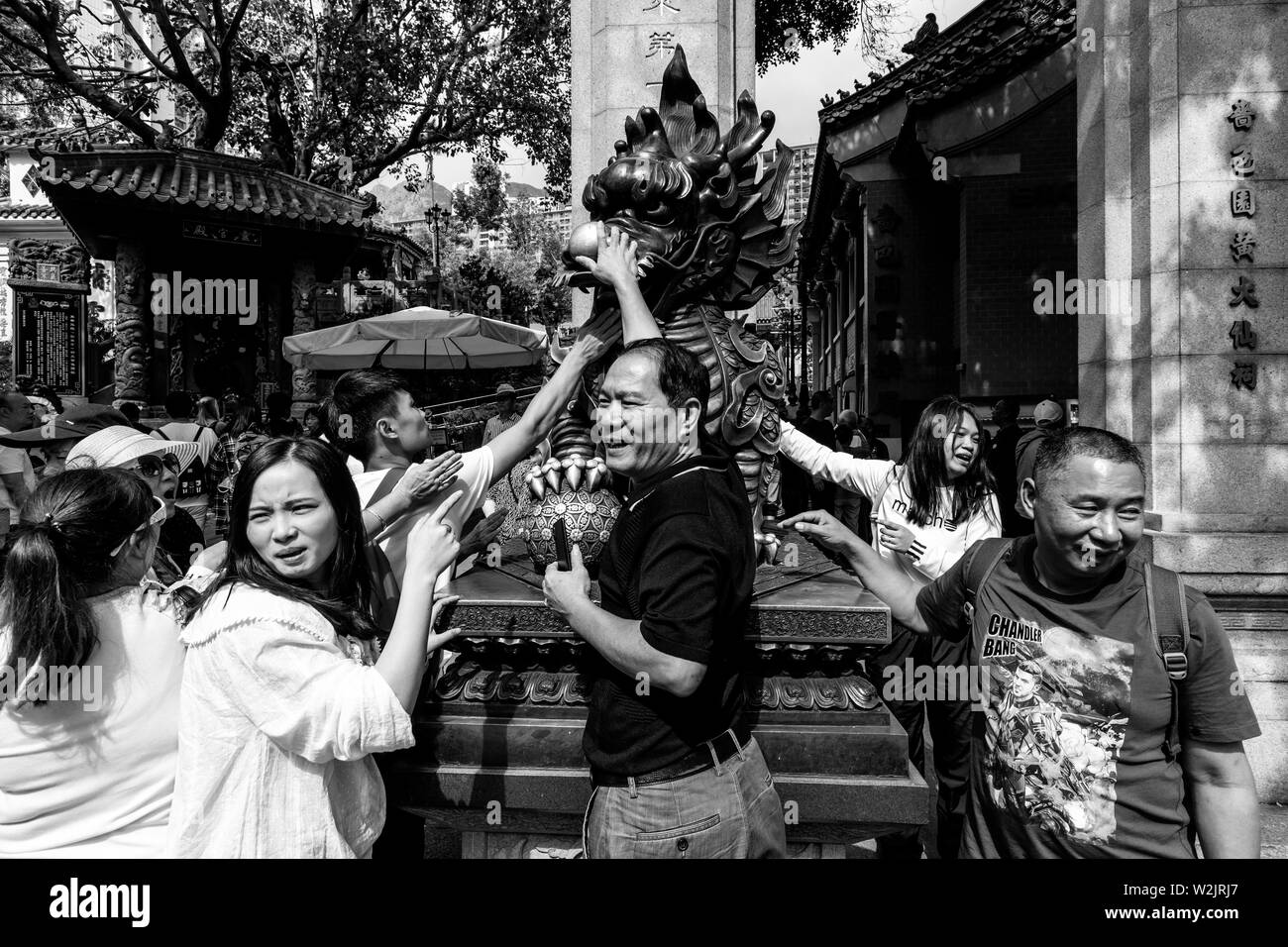 Chinesische Touristen reiben Sie den Drachen Statue für gutes Glück am Eingang zu Wong Tai Sin Tempel, Hongkong, China Stockfoto