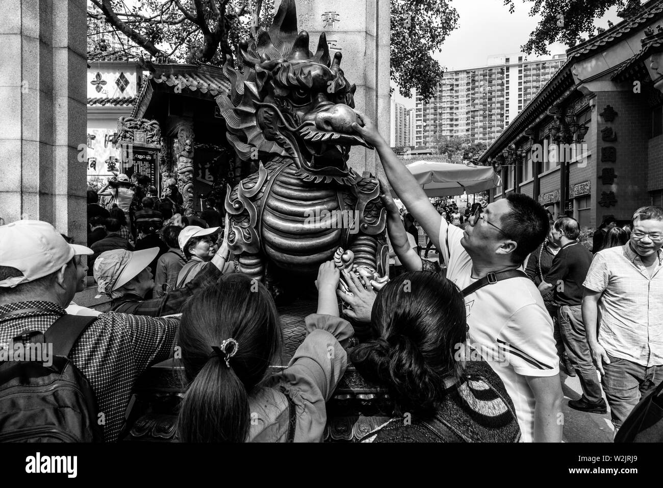 Chinesische Touristen reiben Sie den Drachen Statue für gutes Glück am Eingang zu Wong Tai Sin Tempel, Hongkong, China Stockfoto