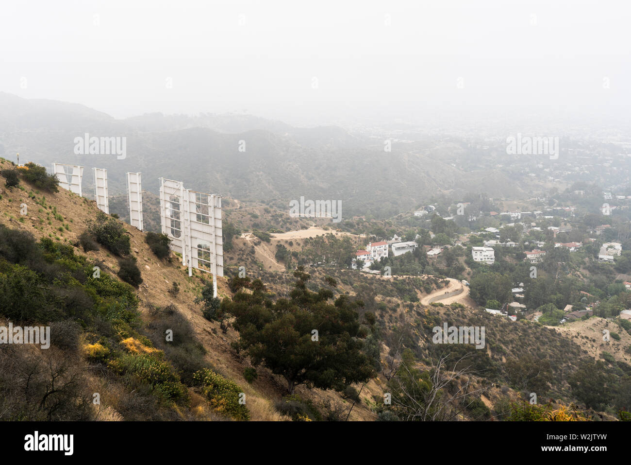 Los Angeles, Kalifornien, USA - 7. Juli 2019: nebeliger Morgen Blick auf den berühmten Hollywood Zeichen und Häuser am Hang in der Nähe von beliebten Griffith Park. Stockfoto