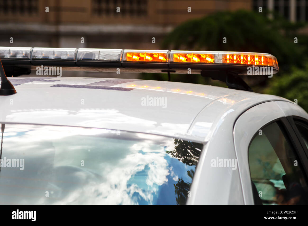 Weiße Polizei Auto mit einem Stroboskop Licht auf dem Dach, die orange  blinkt, um Aufmerksamkeit zu erregen Stockfotografie - Alamy