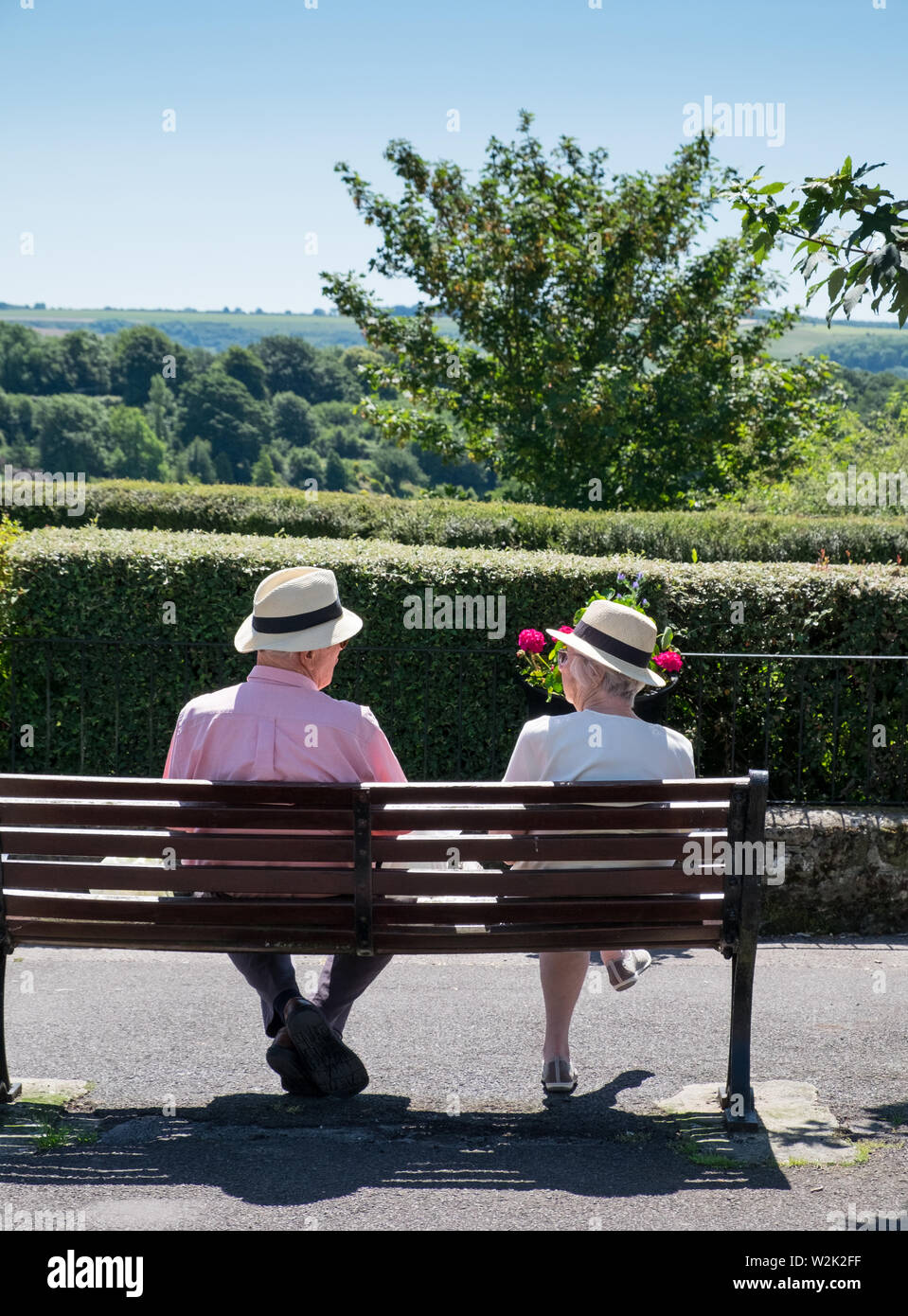 Ältere Rentnerehepaar entspannen auf einer Parkbank, die an der Ansicht von Blackmore Vale in Shaftesbury, Dorset Stockfoto