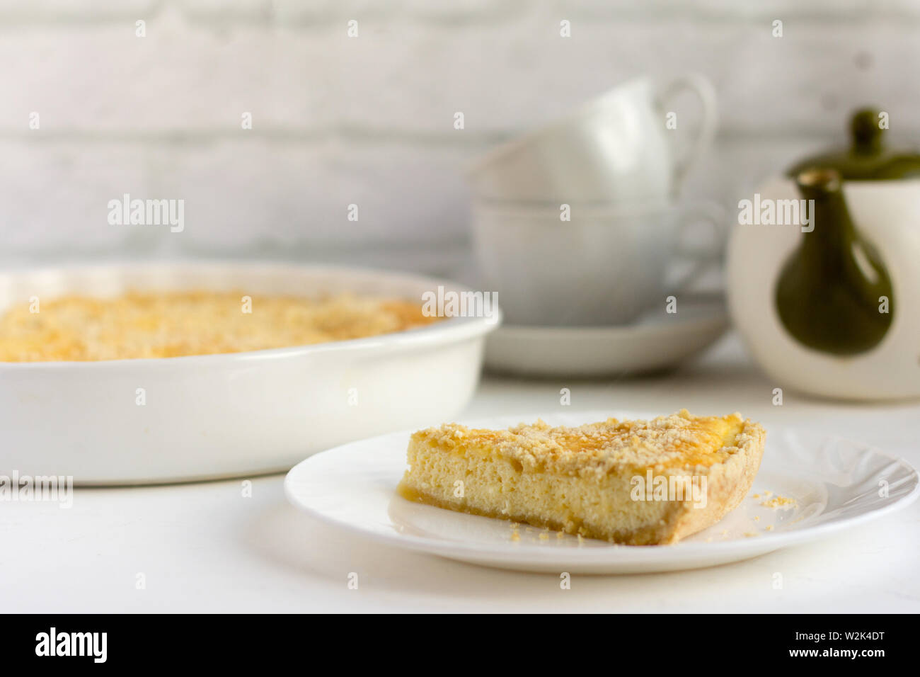 Royal Käsekuchen, leckere frische Cottage Cheese Cake mit Shortbread Cookies und Kaffee Geschirr auf dem Tisch Stockfoto
