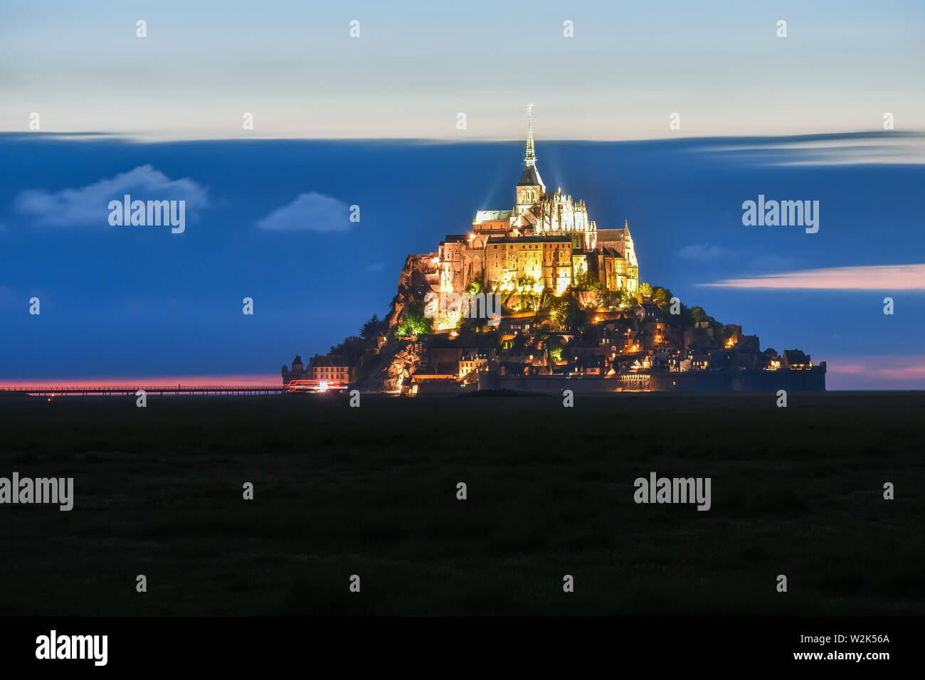 Beleuchtete Mont Saint Michel in der Dämmerung in einer farbenfrohen Himmel mit Wolken auf Sommer, Frankreich Stockfoto