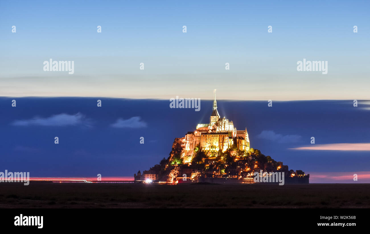Beleuchtete Mont Saint Michel in der Dämmerung in einer farbenfrohen Himmel mit Wolken auf Sommer, Frankreich Stockfoto