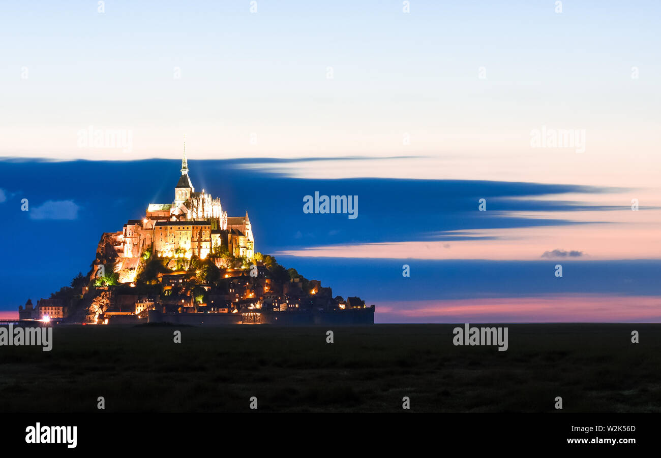 Beleuchtete Mont Saint Michel in der Dämmerung in einer farbenfrohen Himmel mit Wolken auf Sommer, Frankreich Stockfoto