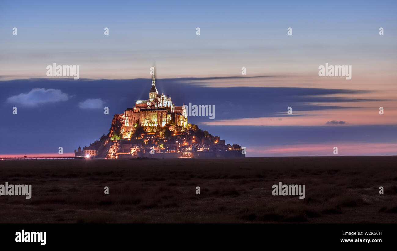 Beleuchtete Mont Saint Michel in der Dämmerung in einer farbenfrohen Himmel mit Wolken auf Sommer, Frankreich Stockfoto