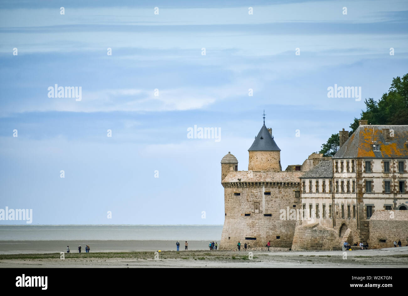 Touristen am Strand und einer der Türme der Mauer von Mont Saint Michel, Frankreich. Stockfoto