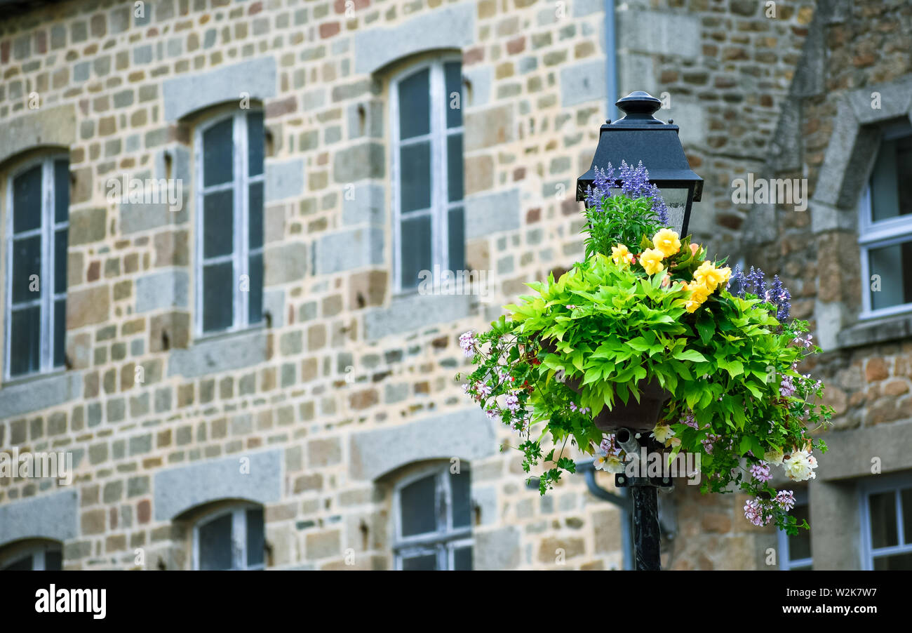 Strassenleuchte geschmückt mit Blumen, mit defokussiertem Hintergrund der typischen Haus der französischen Bretagne. Stockfoto