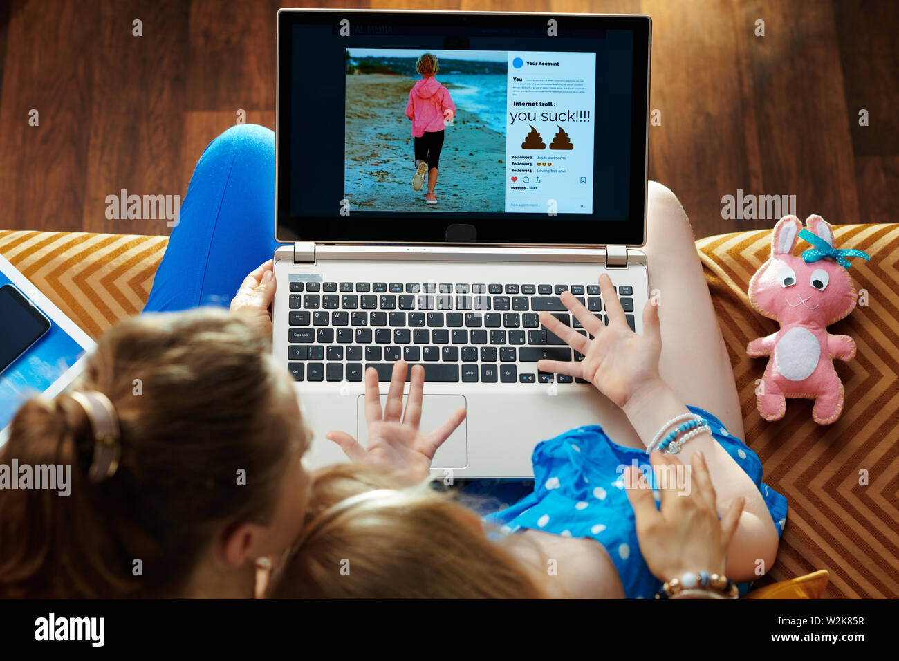 Verärgert moderne Mutter und Tochter sitzen auf der Couch in der modernen Wohnzimmer Leiden von Cyber Mobbing in sozialen Medien auf einem Laptop. Stockfoto