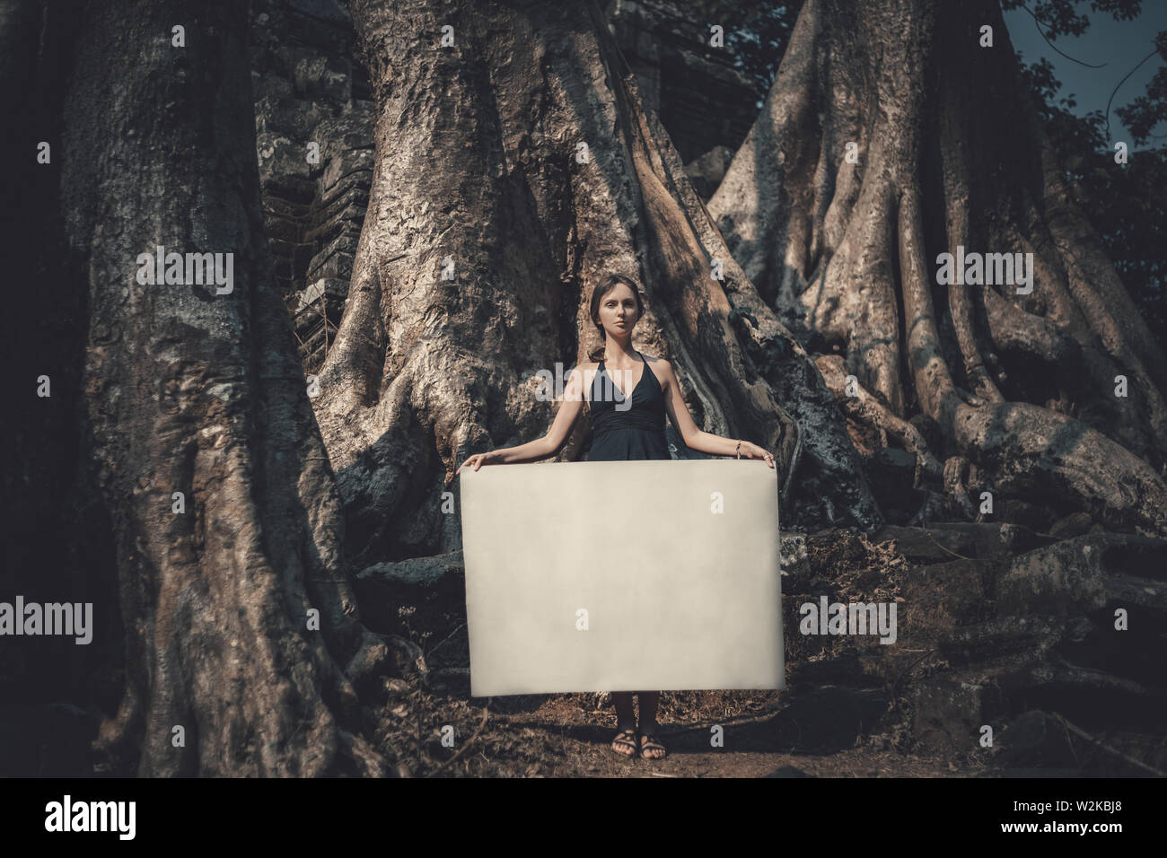 Junge Frau mit leeren Plakat in dunklen mystischen Ort Stockfoto