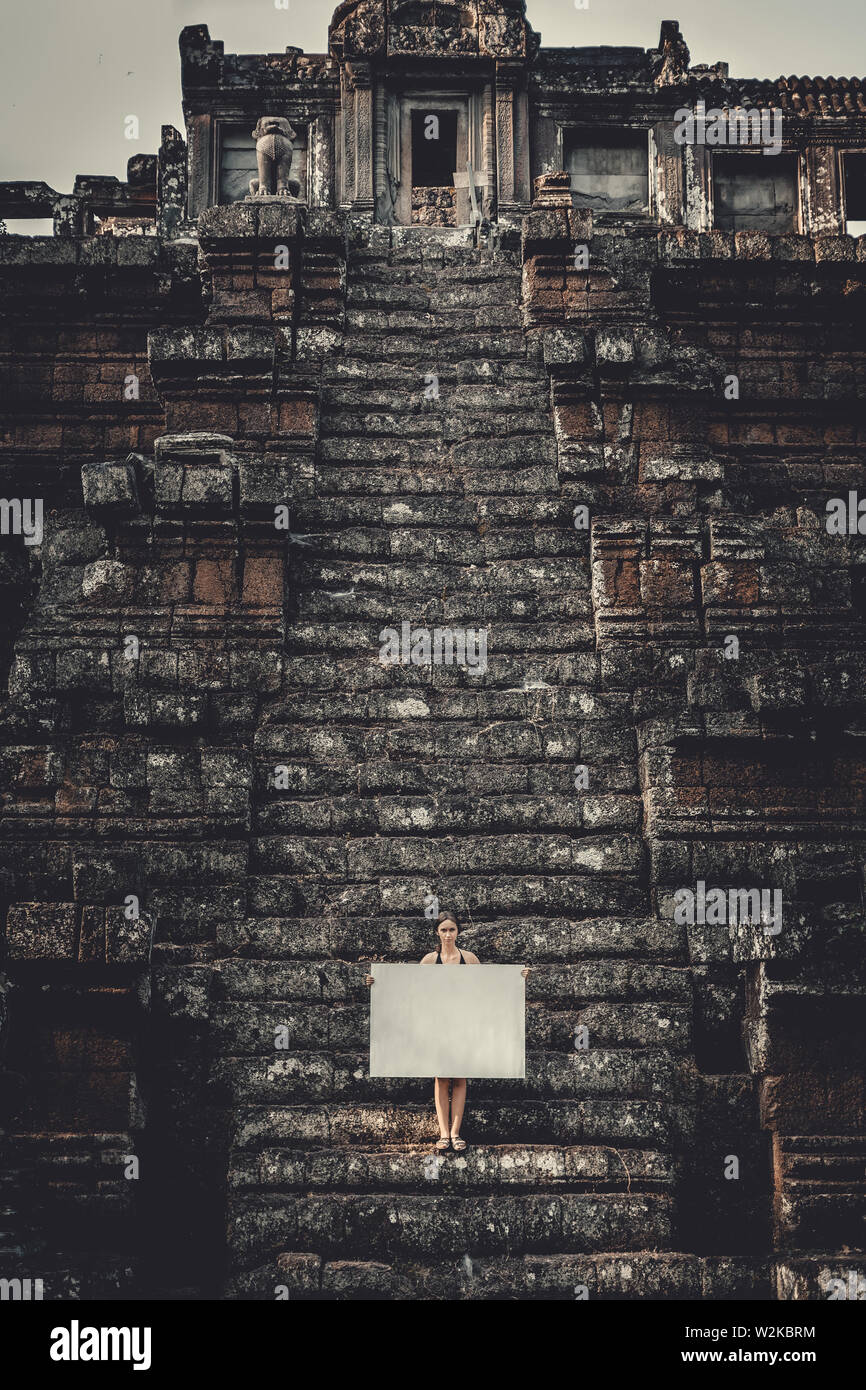 Junge Frau mit leeren Plakat in dunklen mystischen Ort Stockfoto