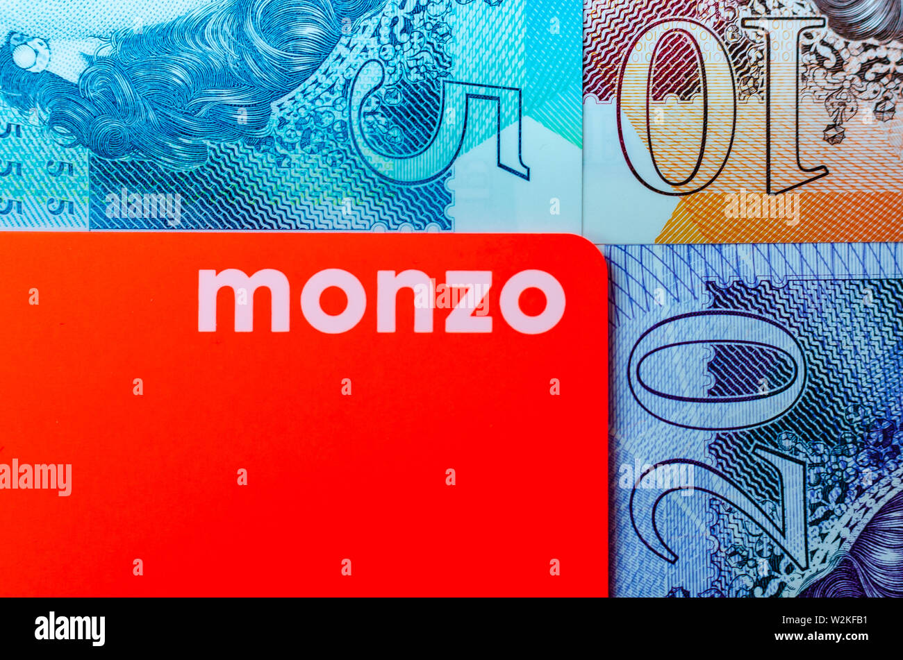 Monzo Bank Card auf dem Hintergrund der britischen Pfund Bargeld unterschiedlicher Konfessionen. Stockfoto