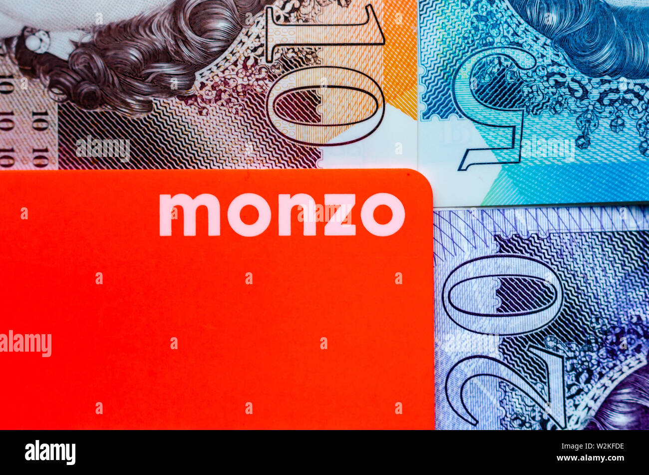 Monzo Bank Card auf dem Hintergrund der britischen Pfund Bargeld unterschiedlicher Konfessionen. Stockfoto