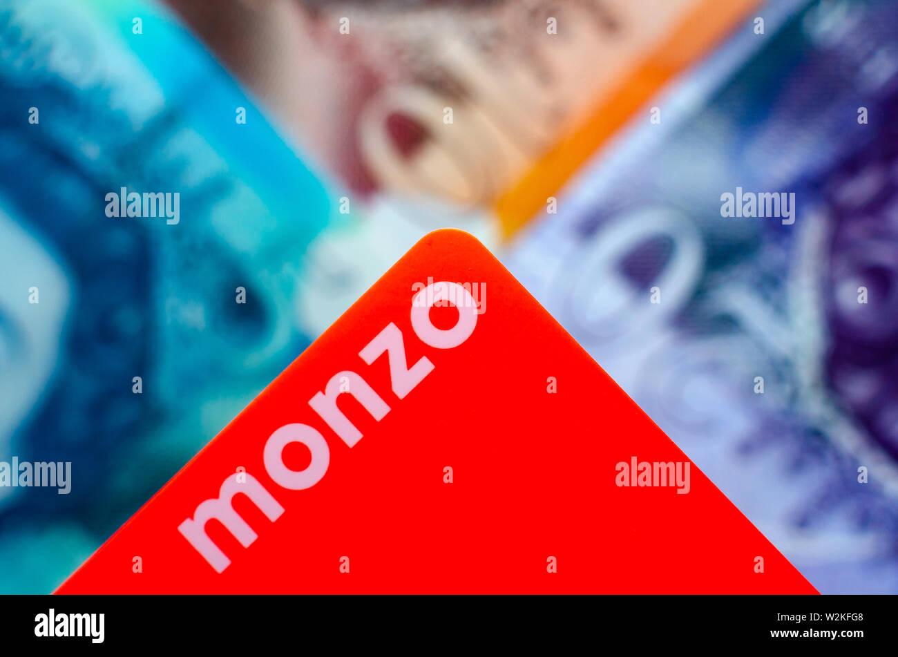 Monzo bank karte auf den verschwommenen Hintergrund der britischen Cash verschiedenen Konfessionen. Stockfoto