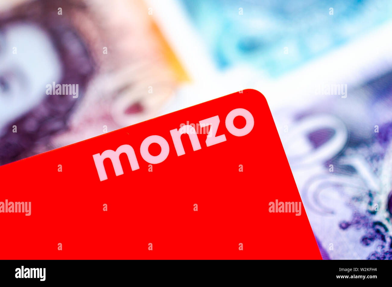 Monzo bank karte auf den verschwommenen Hintergrund der britischen Cash verschiedenen Konfessionen. Stockfoto