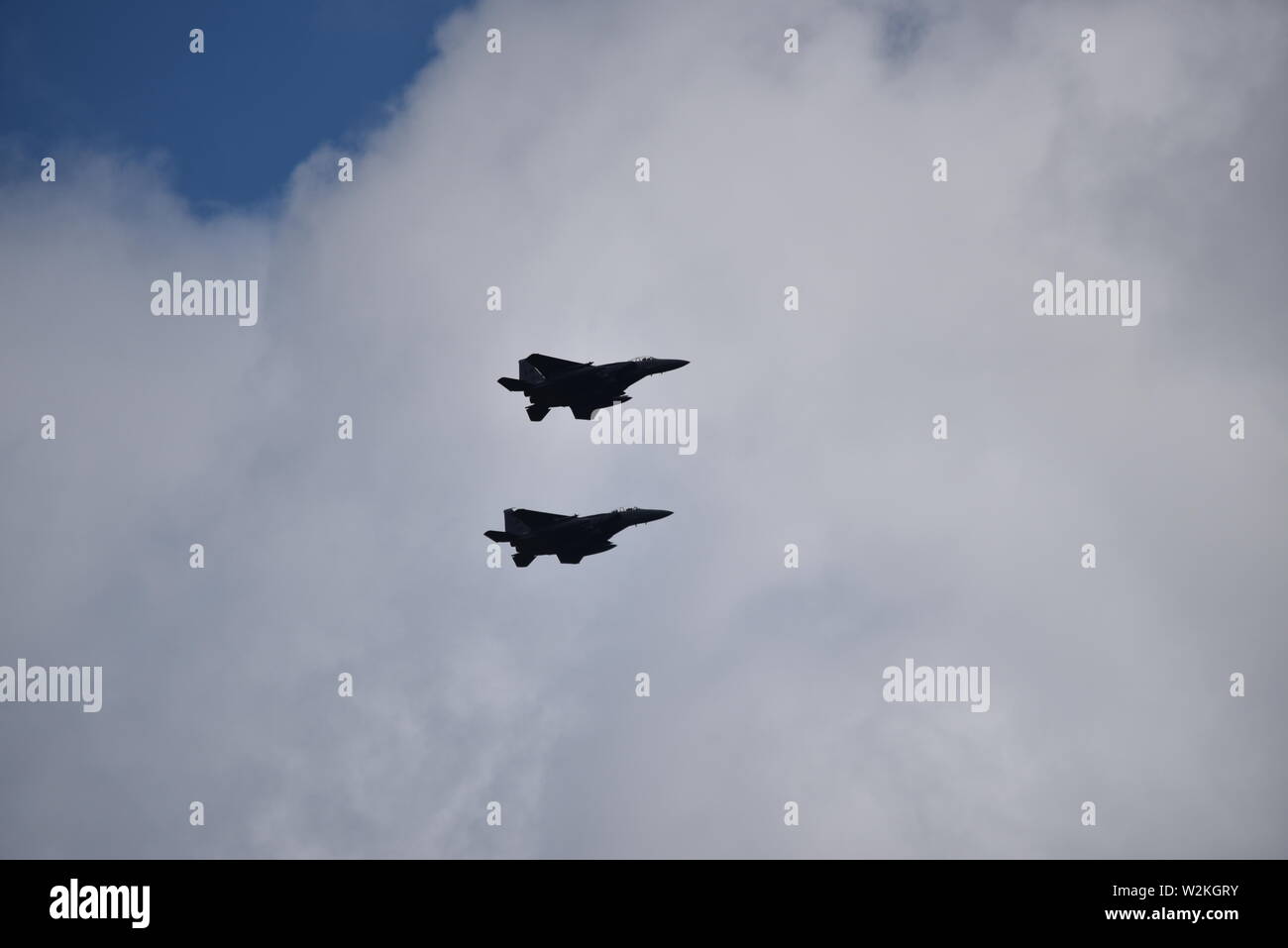 Zwei f15-Kampfflugzeuge mit Silhouette gegen große weiße Wolken Stockfoto