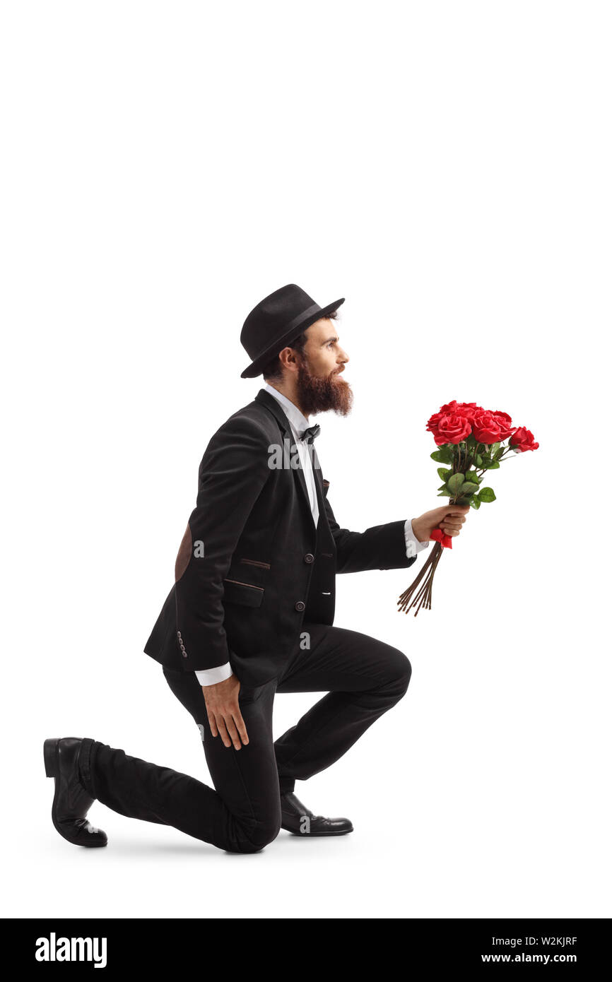 Volle Länge Profil Schuß eines bärtigen Mannes kniend und mit roten Rosen auf weißem Hintergrund Stockfoto Volle Länge Profil Schuß eines bärtigen Mannes kniend und mit roten Rosen auf weißem Hintergrund Stockfoto