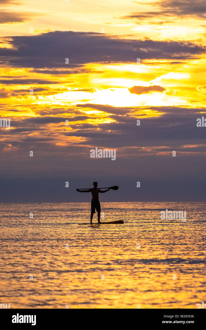 Aberystwyth Wales UK, Dienstag, 09. Juli 2019 UK Wetter: ein Mann gegen die Farben des Sonnenuntergangs paddleboard Silhouette, wie Sie auf dem ruhigen Meer vom Strand aus in Aberystwyth am Ende eines warmen Sommern Tag in West Wales. Photo Credit: Keith Morris // Alamy leben Nachrichten Stockfoto